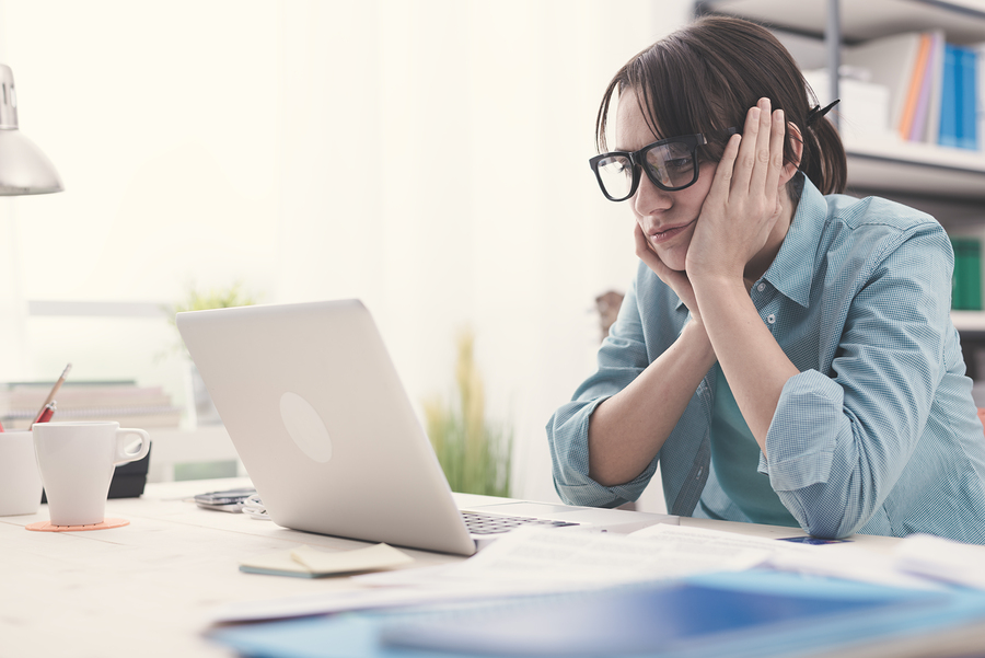 A woman sits at her desk struggling to concentrate on her work.